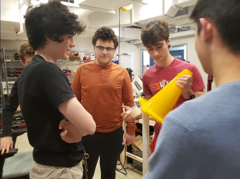 Luke '25, Eli '24, Owen '25, and Maxwell '25 brainstorming robot mechanisms that can pick up and transport cones onto poles.